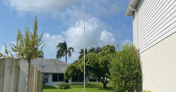 A Greyline DX Flagpole antenna standing in an operator's yard at N3EQF in Florida - a full-length vertical for the low bands, no radials in the ground