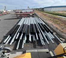 Load image into Gallery viewer, Twelve new CommScope 80-foot galvanized steel monopoles stacked on dunnage in an Idaho yard